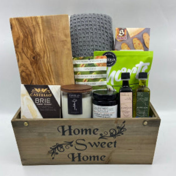 The Home Haven Gift Basket offers the perfect blend of comfort and flavor for any occasion. Nestled in a charming wooden container with “Home Sweet Home” on the front, this thoughtful selection features a cozy blanket, beautiful acacia cutting board, gourmet cheese, locally crafted spread, crackers, all-natural candle, gourmet nuts, handmade shortbread, and a pairing of infused olive oil and balsamic vinegar. Realtor Closing Gifts in Ottawa