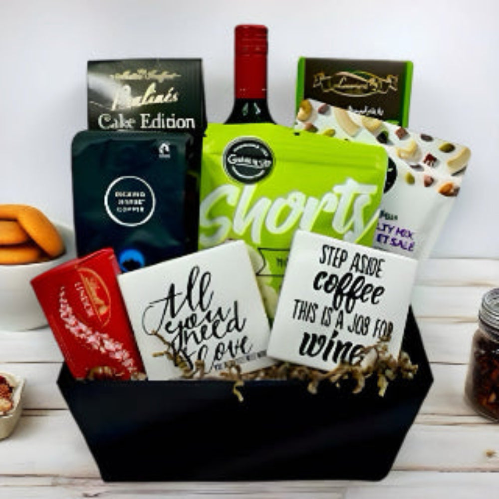 stylish container filled with a bottle of red wine, gourmet coffee, truffles, shortbread, mixed nuts, shortbread and 2 fun coasters
