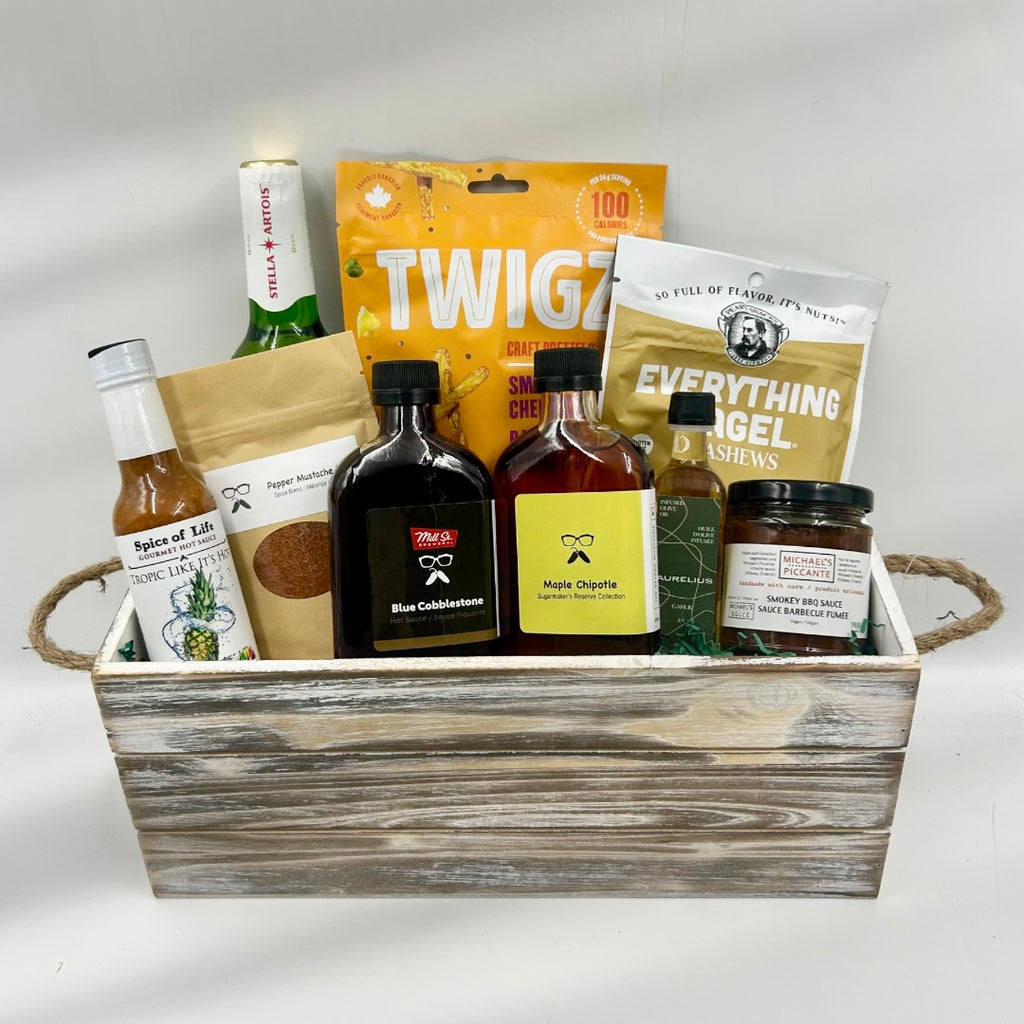 The Rustic Grill Box is a must-have for BBQ and flavor enthusiasts! Packed in a rustic wooden container, this gift includes savory pretzels, seasoned nuts, and a bottle of local craft beer to kick off any gathering. Enjoy a premium selection of local barbeque sauce, infused olive oil, bold hot sauces, and a chipotle maple syrup that adds a unique, smoky-sweet finish to dishes. A specially curated seasoning blend rounds out the collection